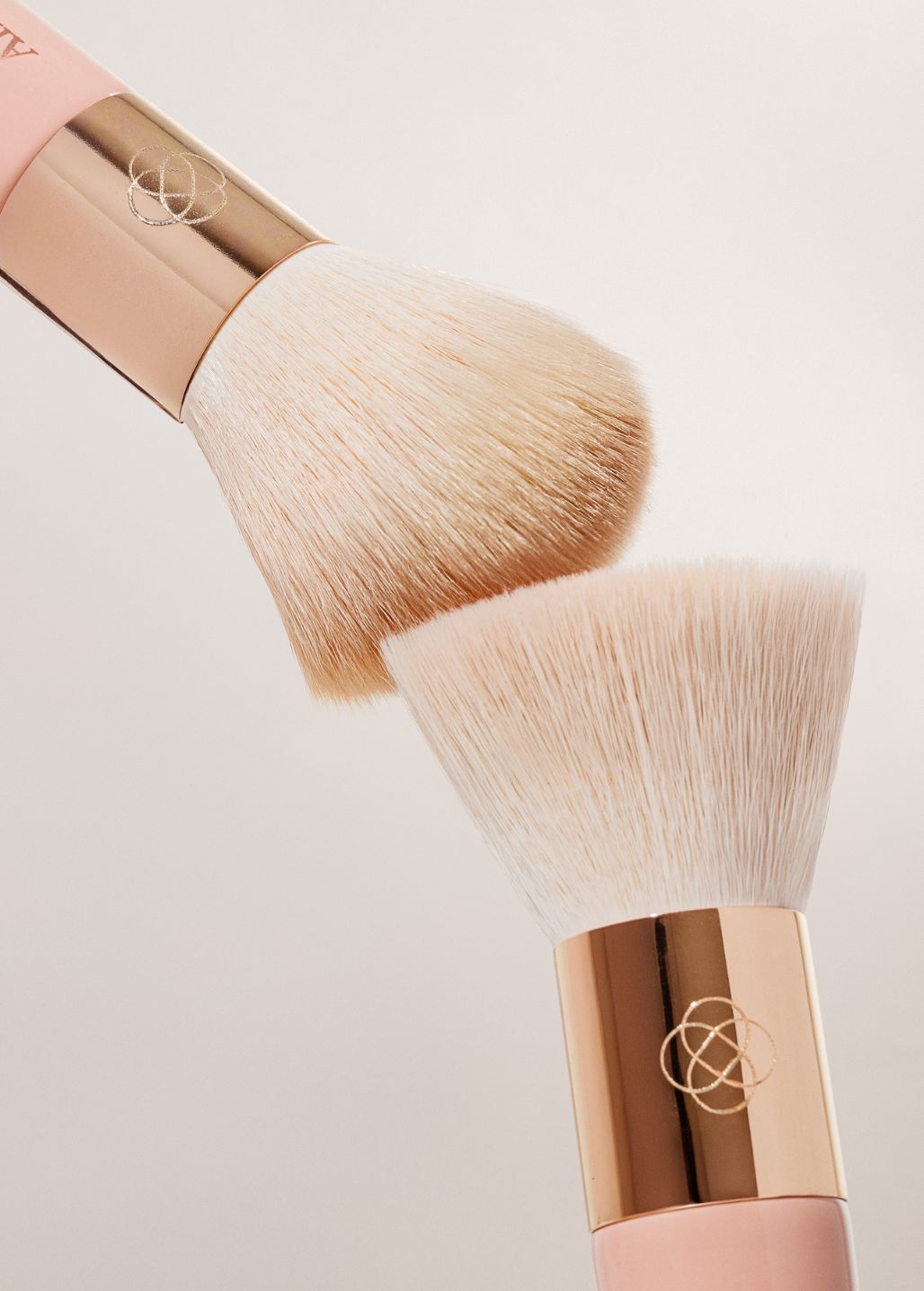 Różowo-złote pędzle kabuki i flat top Annabelle Minerals do makijażu z miękkim włosiem na białym tle