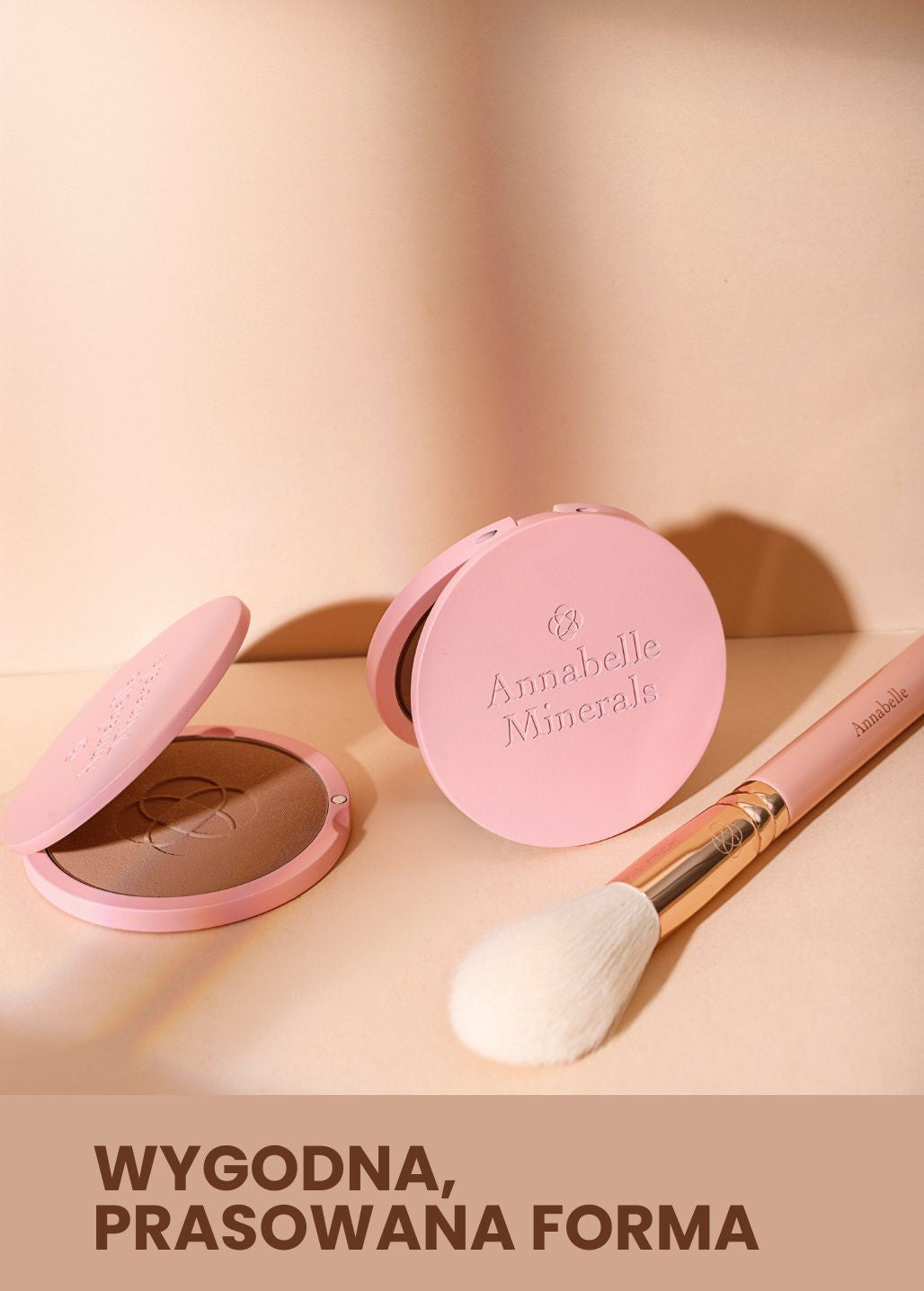 Kompaktowy bronzer mineralny do makijażu w różowym opakowaniu obok puchatego pędzla