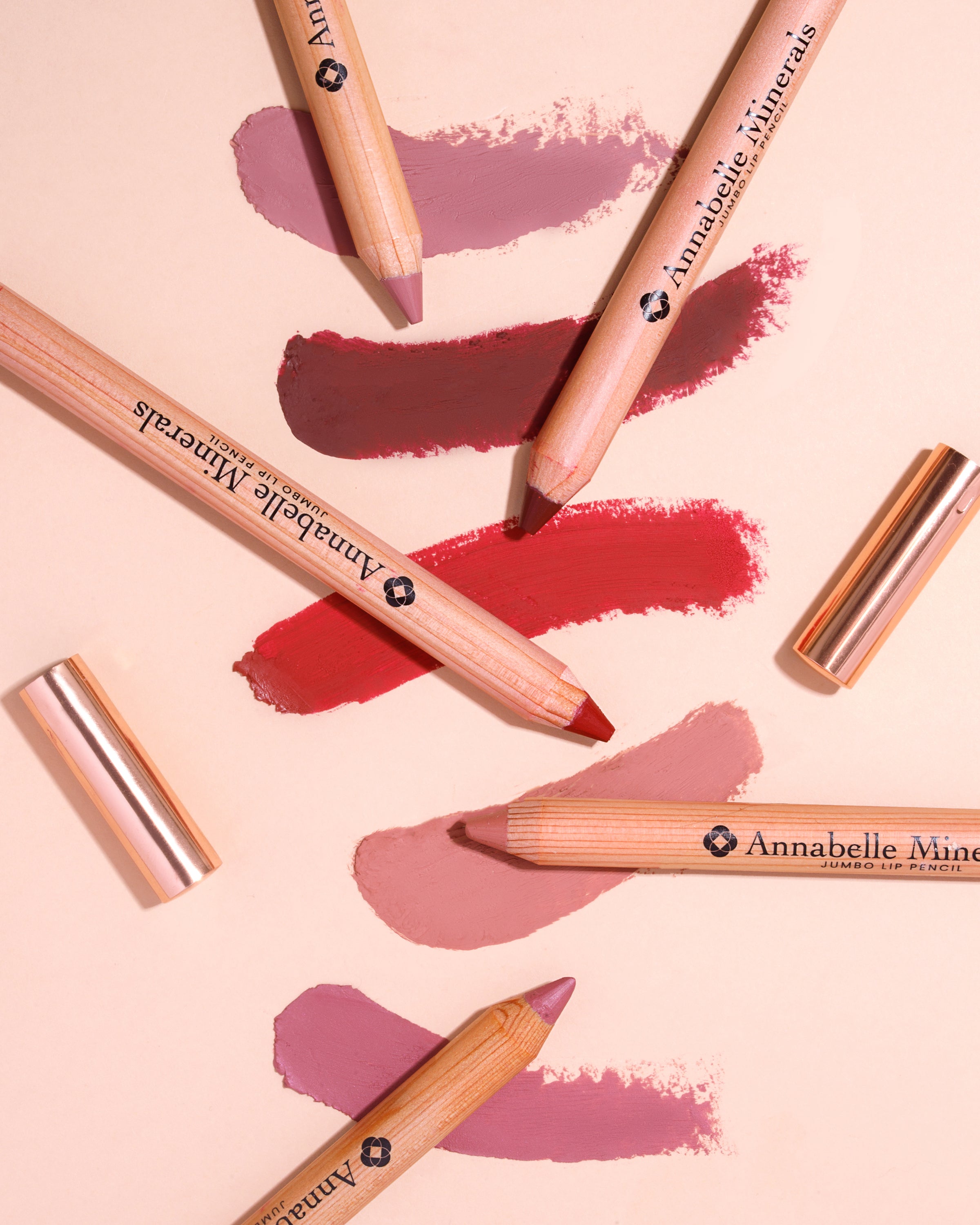 Kredki do ust Annabelle Minerals w różnych odcieniach na lekkim tle z próbkami kolorów