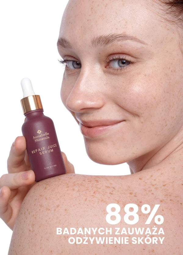 Osoba z uśmiechem trzyma serum Repair Juice Annabelle Minerals w ciemnej butelce, z napisami o odżywieniu skóry