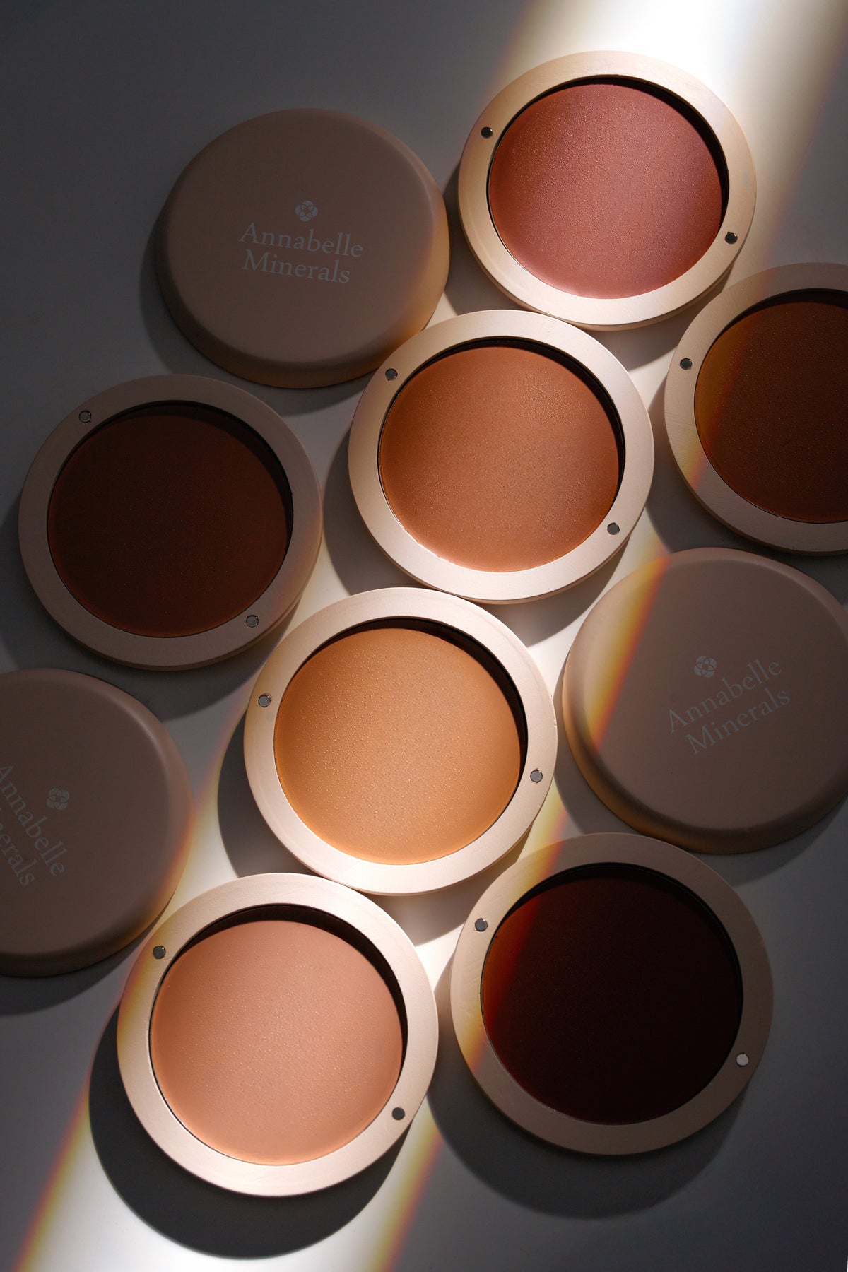 Różne odcienie kremowego bronzera Annabelle Minerals na delikatnym tle