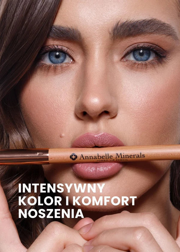 Osoba z niebieskimi oczami i ciemnymi włosami trzyma kredkę do ust jumbo Annabelle Minerals przy ustach