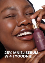 Uśmiechnięta osoba trzymająca butelkę serum Repair Juice z hasłem o zmniejszeniu sebum w ciągu 4 tygodni