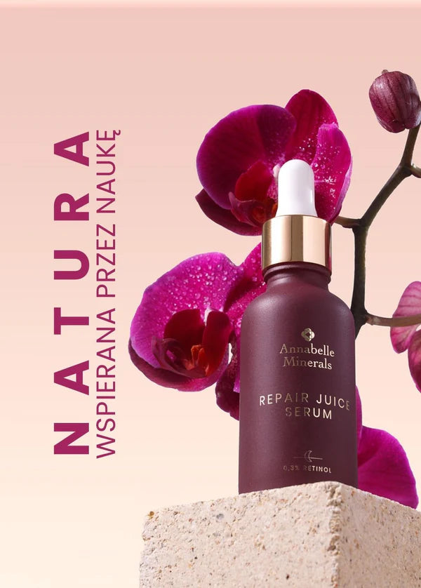 Butelka serum Repair Juice Annabelle Minerals do pielęgnacji skóry obok kwiatu orchidei na teksturowanej powierzchni