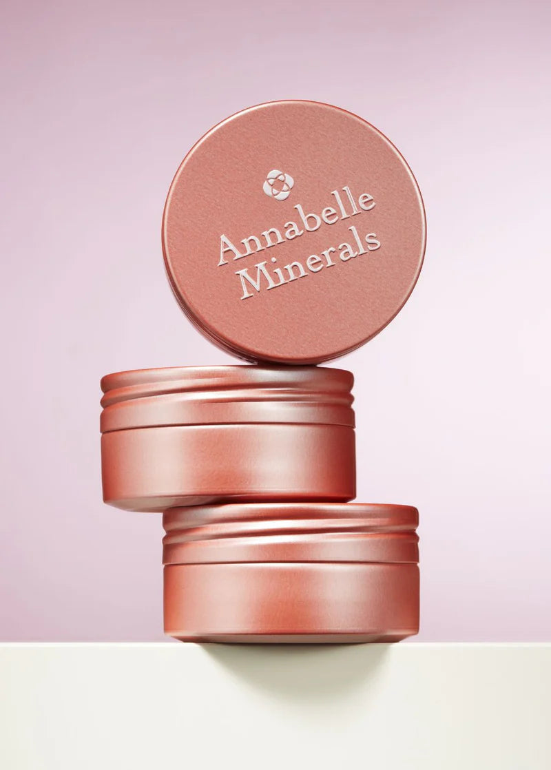 Trzy cylindryczne pojemniki w jasnoróżowym kolorze, z napisem Annabelle Minerals na pokrywce