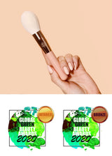 Ręka trzymająca pędzel do pudru Annabelle Minerals z dwoma nagrodami Global Green Beauty Awards 2020