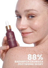 Osoba z uśmiechem trzyma serum Repair Juice Annabelle Minerals w ciemnej butelce, z napisami o odżywieniu skóry