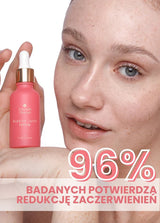 Osoba trzyma butelkę różowego serum Clarity Juice Annabelle Minerals do pielęgnacji skóry z napisem 96% REDUKCJA ZACZERWIENIEŃ