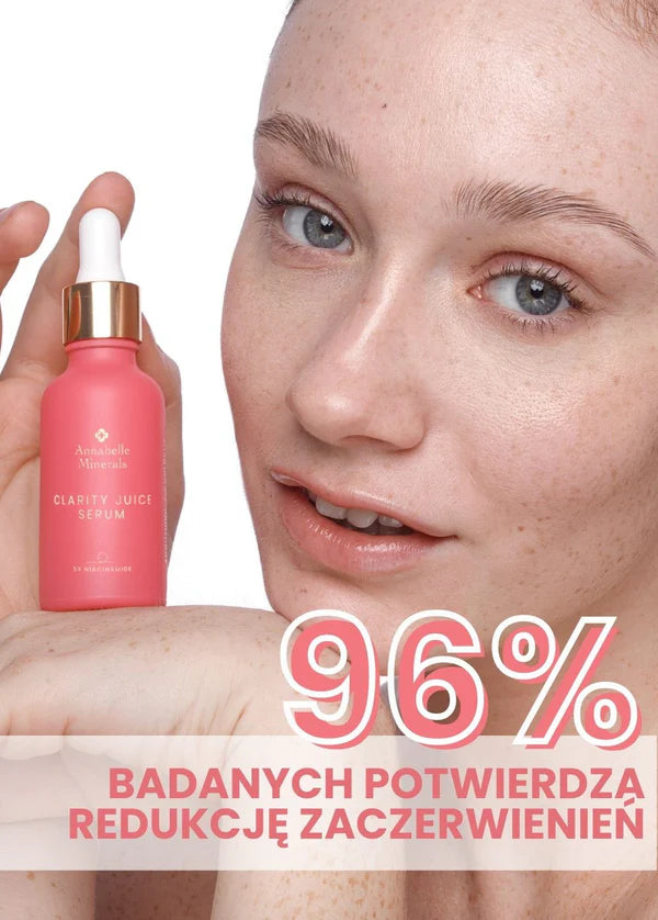 Osoba trzyma butelkę różowego serum Clarity Juice Annabelle Minerals do pielęgnacji skóry z napisem 96% REDUKCJA ZACZERWIENIEŃ