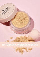Otwarty pojemnik z rozświetlaczem mineralnym Royal Glow Annabelle Minerals i małą gąbką do makijażu na różowym tle